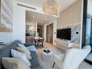 a living room with a blue couch and a tv at Key View - Sobha Waves in Dubai
