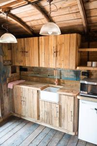 a kitchen with wooden cabinets and a white sink at Swallowfield Glamping-Station Master in Yeovil