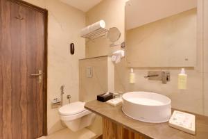 a bathroom with a white sink and a toilet at Lemon Tree Hotel, Kasauli in Kasauli