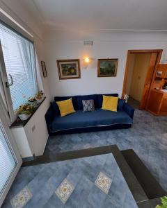 Sofá azul en la sala de estar con almohadas amarillas en Appartamento La Follicara en Anacapri
