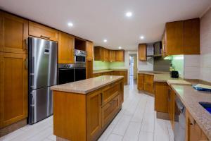 a kitchen with wooden cabinets and a stainless steel refrigerator at Villa Freesia with heated pool and air conditionin in San Miguel de Abona