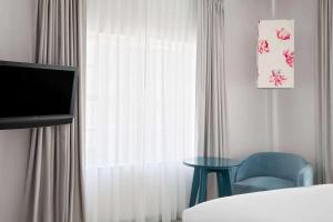 a bedroom with a window with a blue chair and a table at Townhouse Hotel by LuxUrban in Miami Beach