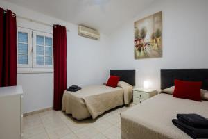 a bedroom with two beds and a window with red curtains at Villa Freesia with heated pool and air conditionin in San Miguel de Abona +26 photos