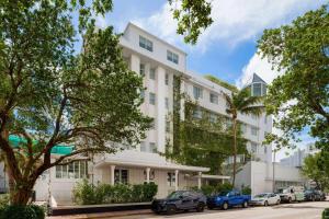 un edificio blanco con coches estacionados frente a él en Townhouse Hotel by LuxUrban en Miami Beach