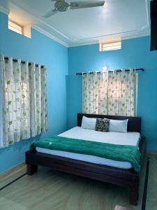 1 dormitorio con 1 cama con paredes y cortinas azules en The Bainada farm, en Jaipur