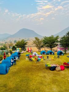 un grupo de tiendas de campaña en un campo con mesas y sillas en The Bainada farm, en Jaipur