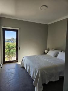 1 dormitorio con cama grande y ventana grande en Soltroia Beach River & Golf, en Grândola