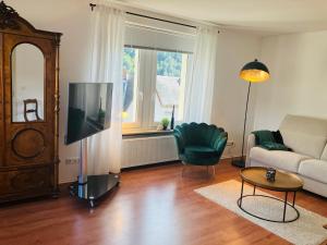 un soggiorno con TV, divano e sedia di NEU - Ferienwohnungen im Winzergarten a Traben-Trarbach