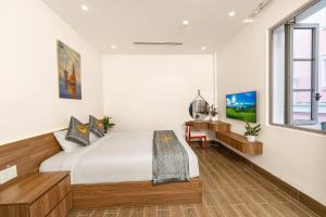 a bedroom with a bed and a desk at Alba Sand Hotel & Spa Phú Quốc in Phu Quoc