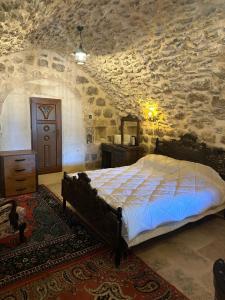 a bedroom with a bed and a stone wall at Rumet paşa konağı in Mardin