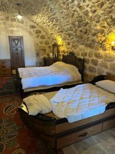 a bedroom with two beds and a stone wall at Rumet paşa konağı in Mardin