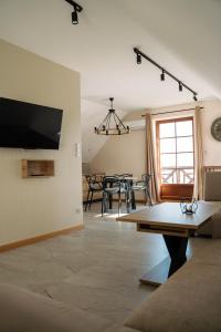 a living room with a table and a tv on a wall at Apartament Portowy in Mikołajki