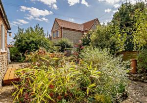 a garden in front of a house with plants at Hidden Loke Cottage in Blakeney