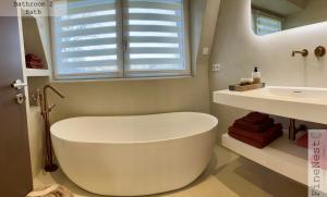 eine weiße Badewanne im Bad mit Waschbecken in der Unterkunft Villa 3 chambres "La luxueuse Ardennes" by FineNest in Chaudfontaine