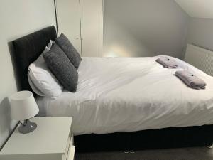 a large bed with white sheets and pillows on it at Marshfield House in Goole