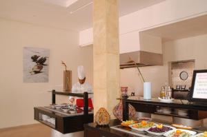 a chef in a kitchen with a buffet of food at Le Petit Palais Djerba & Spa in Houmt Souk