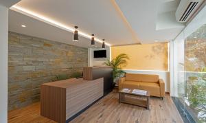 una oficina con una pared de piedra, un sofá y una mesa en Treebo Tryst Vapr Ashok Nagar, en Chennai