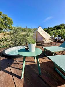 a table with a potted plant on a deck with a tent at Stecadó Glamping in Dolceacqua