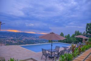 einen Pool mit einem Tisch, Stühlen und einem Sonnenschirm in der Unterkunft Humphreys HillHouse in Kisii