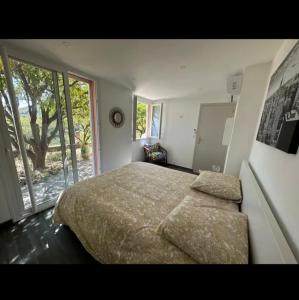 a bedroom with a large bed and a large window at 10 min de Monaco petite maison avec jardin vue mer et rocher de Monaco in La Turbie