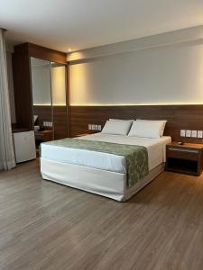 a bedroom with a large bed and a mirror at Vista Azul Apart Hotel - Vista Pinheiros in Pedra Azul