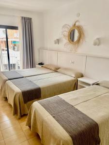 three beds in a room with a mirror on the wall at Hotel Stella Maris in Blanes