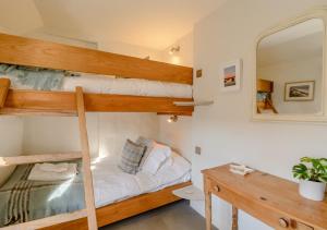 a bedroom with two bunk beds and a mirror at Parsley Cottage in Blakeney