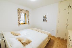 a white bedroom with a bed and a mirror at Rogla Alpina Residence in Zreče