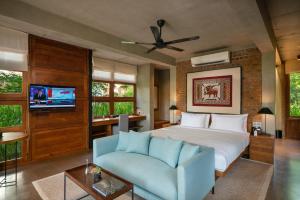 a bedroom with a bed and a couch and a tv at Taru Villas Maia - Habarana in Habarana