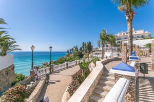 a pathway next to the ocean with palm trees at Los Huertos de Nerja 6 in Nerja