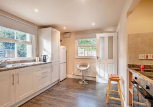 una cucina con armadi bianchi e sgabello di Willow Cottage - Corpusty a Briston