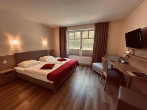 a bedroom with a bed and a desk and a window at Haags Hotel Niedersachsenhof in Verden
