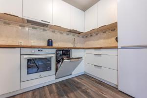 une cuisine avec des armoires blanches et un four dans l'établissement Seaside Apartments - Jūros apartamentai, à Klaipėda