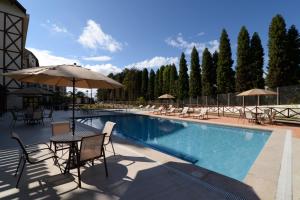 a pool with chairs and tables and an umbrella at Vista Azul Apart Hotel - Vista Pinheiros in Pedra Azul