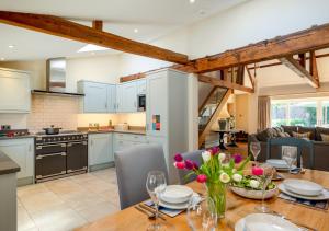 a kitchen and living room with a wooden table with flowers at Boat Barn Cottage 6 in Blakeney