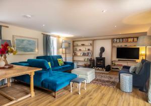 a living room with blue furniture and a tv at Valley House in Cley next the Sea