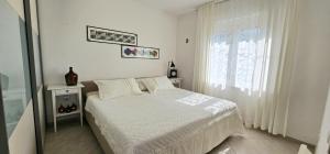 a white bedroom with a bed and a window at Apartman Doris in Dramalj