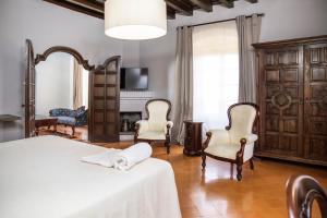 ein Schlafzimmer mit einem Bett und Stühlen sowie einem Kamin in der Unterkunft RVHotels Palau Lo Mirador in Torroella de Montgrí + 84 Fotos