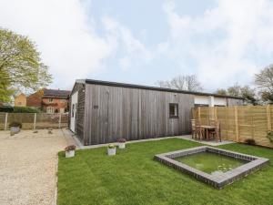 een achtertuin met een klein huis met een vijver bij Oldwyche Barns in Warwick