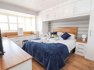 um quarto com uma cama com lençóis azuis e brancos em Beachway em Prestatyn