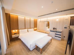 a bedroom with a large white bed and a kitchen at Hôtel de Ľeau in Anping