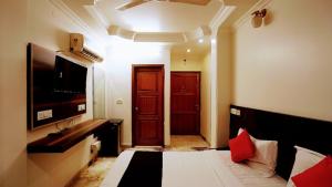 a bedroom with a bed and a television and a door at Hotel De Huespedes near international airport in New Delhi