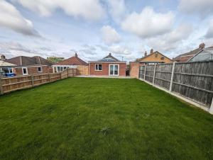 einen Hinterhof mit einem Zaun und einem grünen Garten in der Unterkunft Clovelly Rise in Lowestoft
