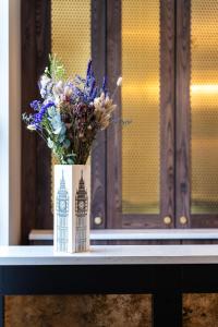 un jarrón de flores sobre una mesa con un edificio en él en The House on Warwick en Londres