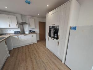 a kitchen with white cabinets and a refrigerator at Clovelly Rise in Lowestoft