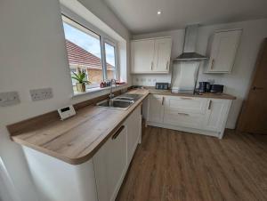 eine Küche mit weißen Schränken, einem Waschbecken und einem Fenster in der Unterkunft Clovelly Rise in Lowestoft