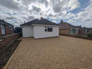 a white house in a yard with houses at Clovelly Rise in Lowestoft