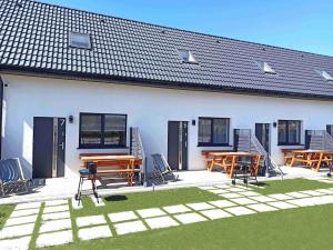 a white house with tables and chairs in a yard at MILAN Domki Mielno in Mielno