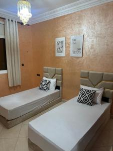 Cette chambre comprend deux lits et un lustre. dans l'établissement Luxury Modern Apartment, à Béni Mellal