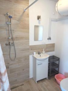 La salle de bains est pourvue d'un lavabo blanc et d'une douche. dans l'établissement MILAN Domki Mielno, à Mielno